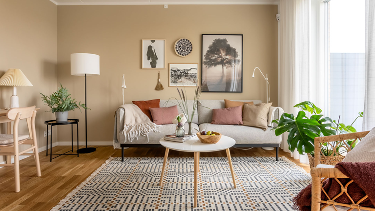 Lys stue med hvidt sofabord, planter, billeder på væggen og en lys sofa
